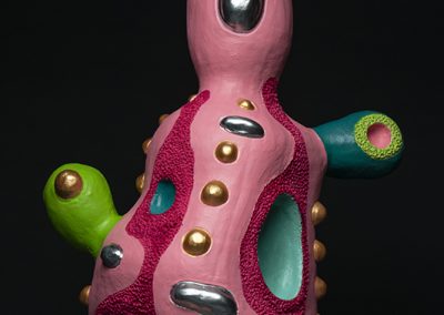 A bright pink sculpture with irregular shape and bright patches.