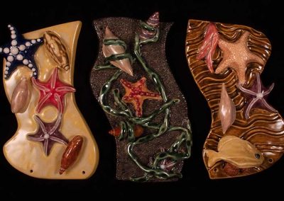 Three clay pieces depicting different types of sea animals and beaches.