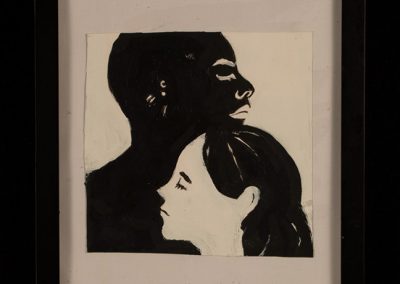 A print of a black person and a white persons faces cradled into one another.