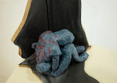 A sculpture that is in the fetal position on a pedestal in the gallery.
