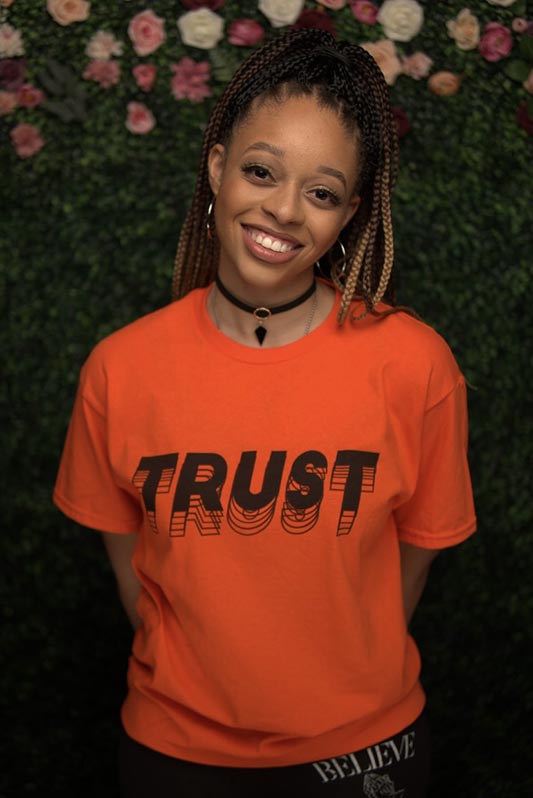 Sara Lane smiling in a "Trust" t-shirt.