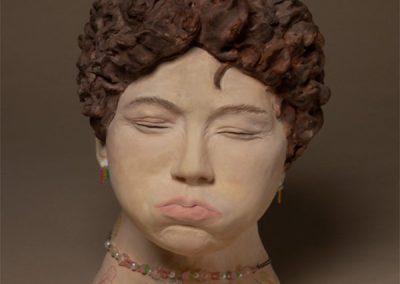 A sculpture of a woman whose face is pinched as she holds her breath.