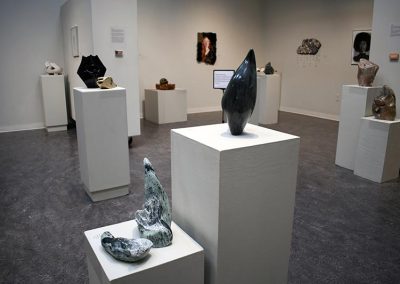 Wide view of sculptures on pedestals and artwork on walls.