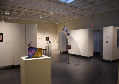 A wide view of the memoirs gallery showing sculptures, multimedia pieces, and flat art.