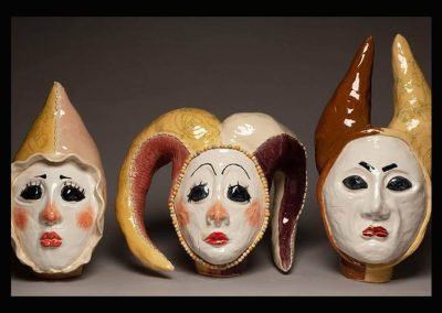 Three sculptures of jesters faces.