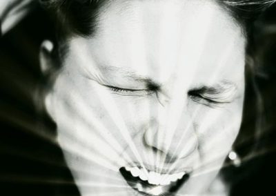 Artwork of a person scrunching their face while their mouth is open and lines as if a sunburst coming out of their mouth.